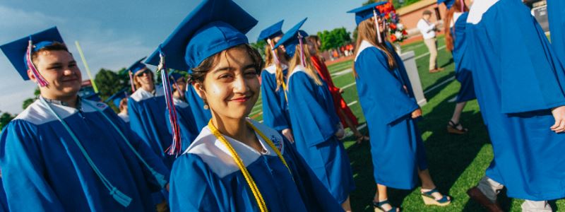 Students walking in cap and gown at graduation ceremony