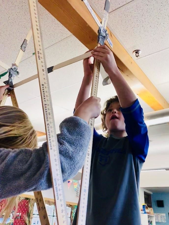 Students building a structure with meter sticks 