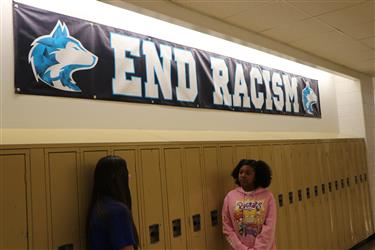 students talking in front of end racism banner