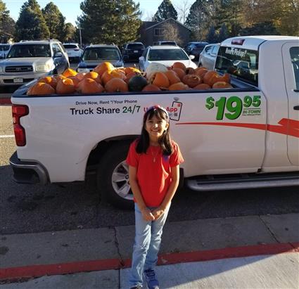  Anjali standing in front of a pickup bed full of pumpkins